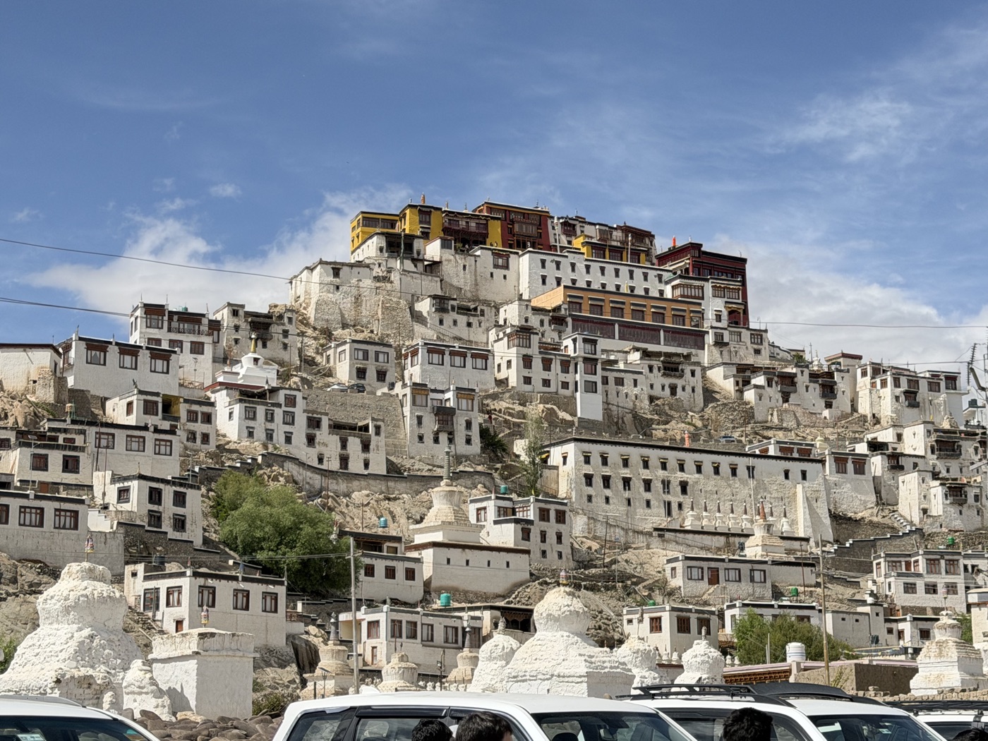 Thiksey Monastery rising above the Indus Valley, white stupas in the foreground against the ochre monastery buildings
