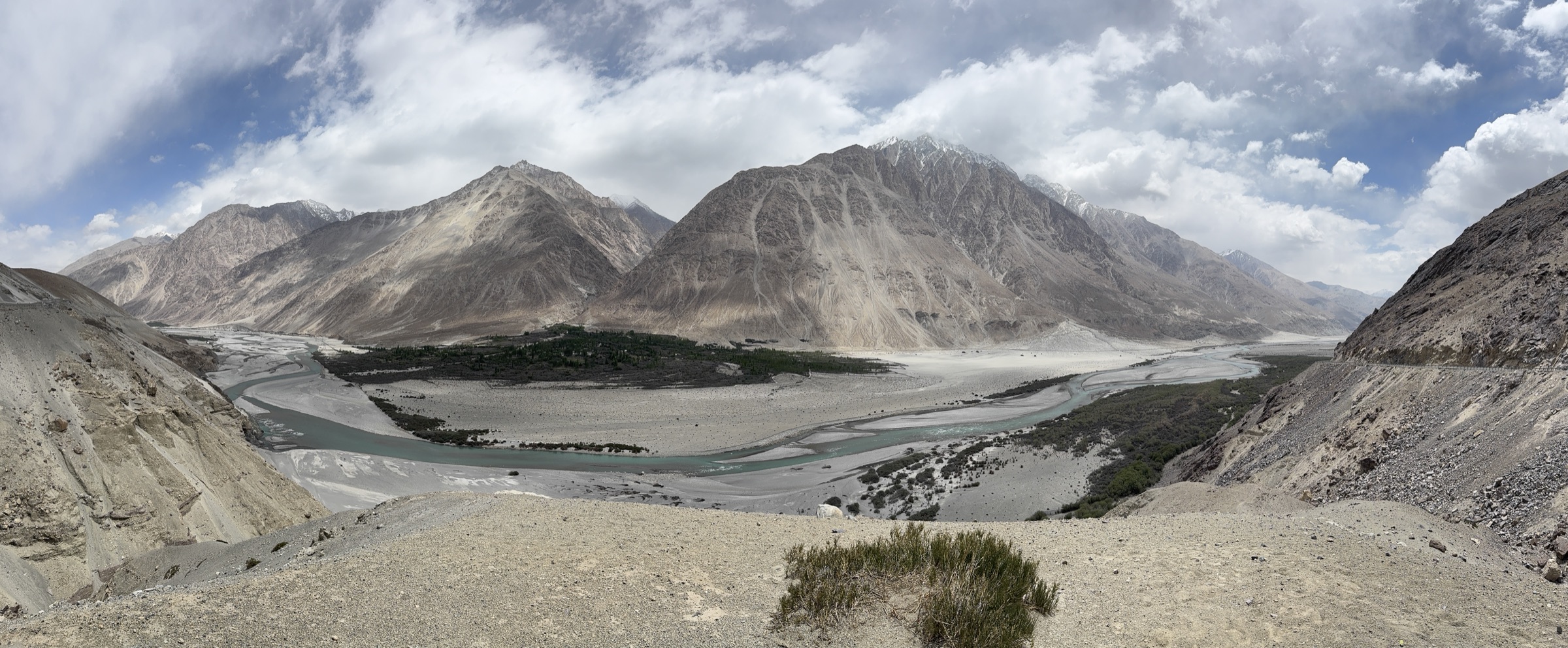 Panoramic view of Nubra Valley — a vast plain with a braided glacial river, enclosed by towering Himalayan ranges