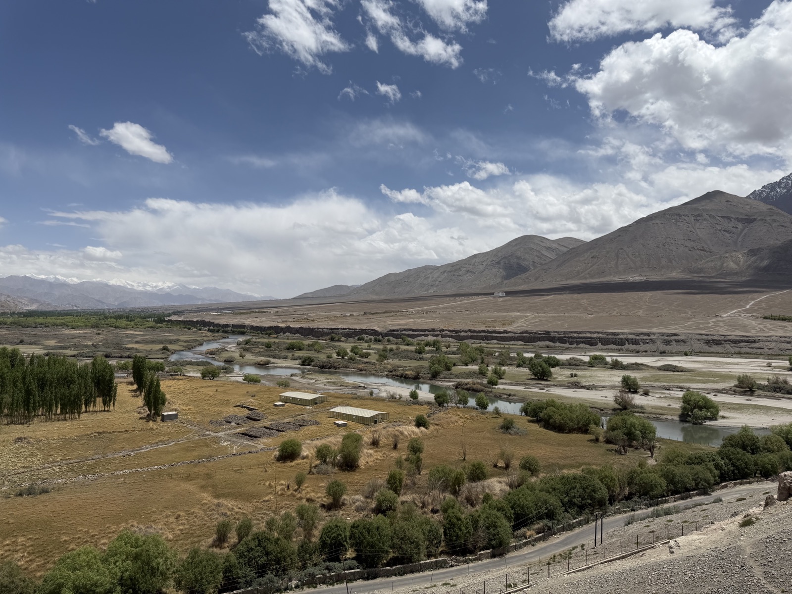 Looking down at the Indus Valley from elevation — a green ribbon of trees and farmland threading through the mountain desert